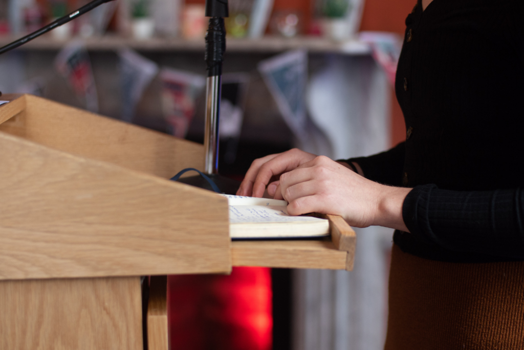 Close up shot of podium with notebook and hands resting on it