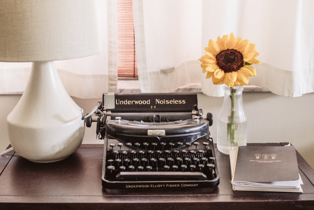 Typewriter on a desk beside a sunflower